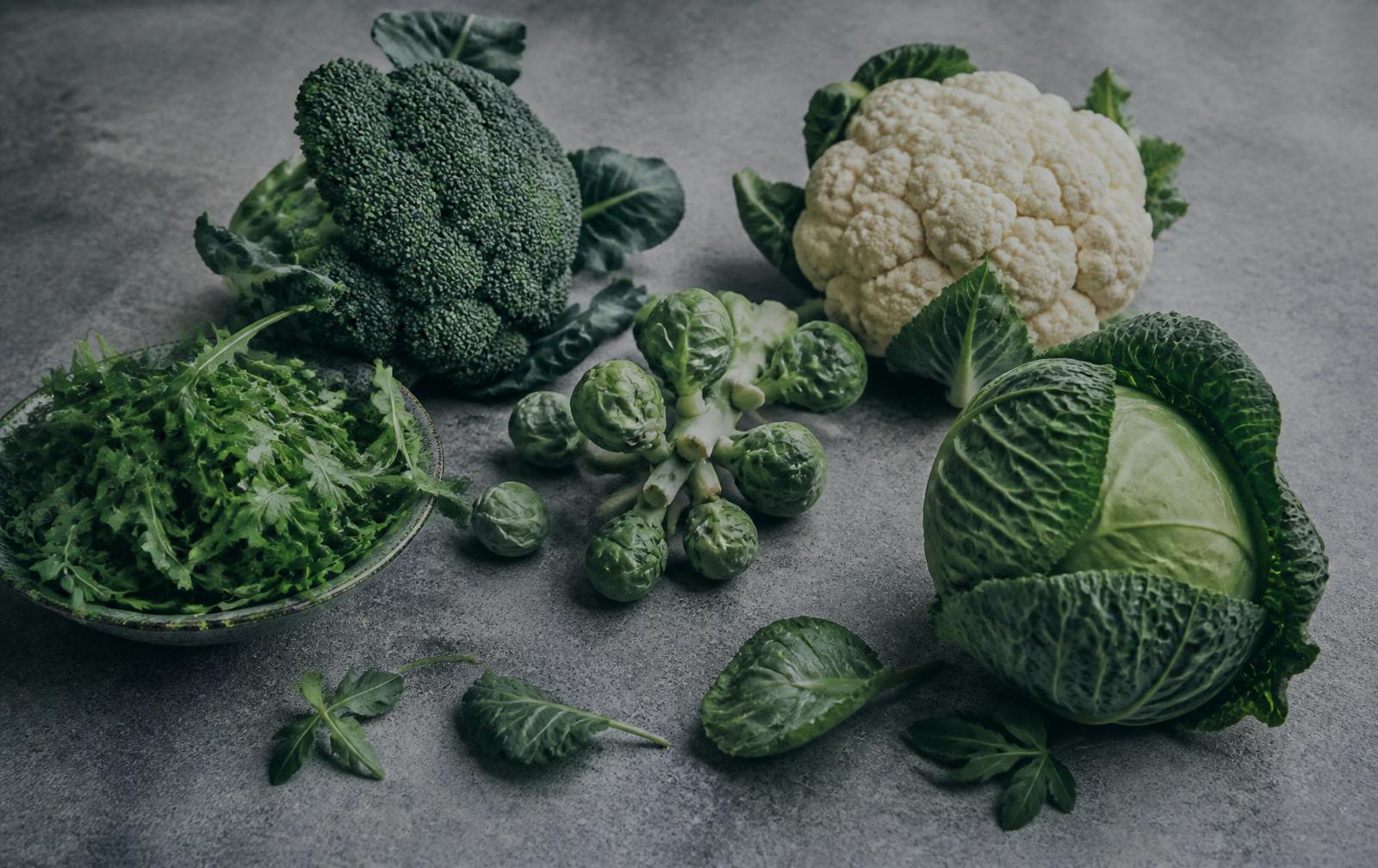 Brócoli, coliflor, coles de Bruselas, repollo y rúgula sobre piedra gris